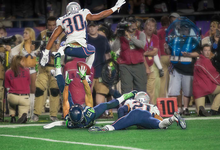 On his back, Jermaine Kearse reaches for a catch between two Patriots defenders during the fourth quarter of Super Bowl 49